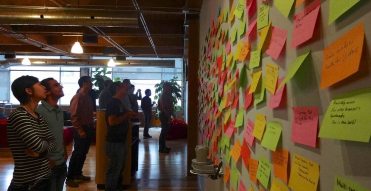 wall of post-it notes with people looking at it