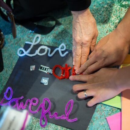 Photo of hands touching piece that reads "love is powerful"
