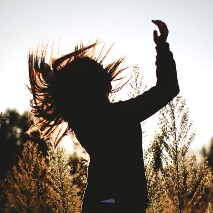 Backlit person dancing in a field